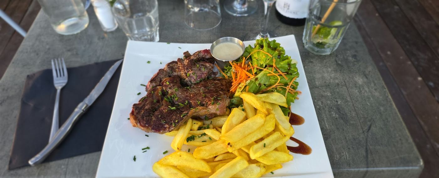 Entrecôte grillée, frites dorées et salade verte sur une assiette carrée