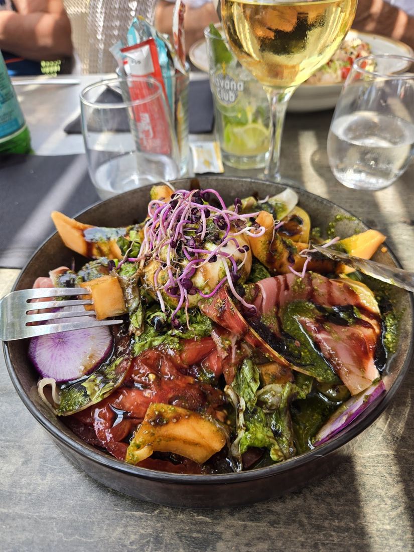 Salade de burrata, melon, tomates et pesto, parsemée de jeunes pousses
