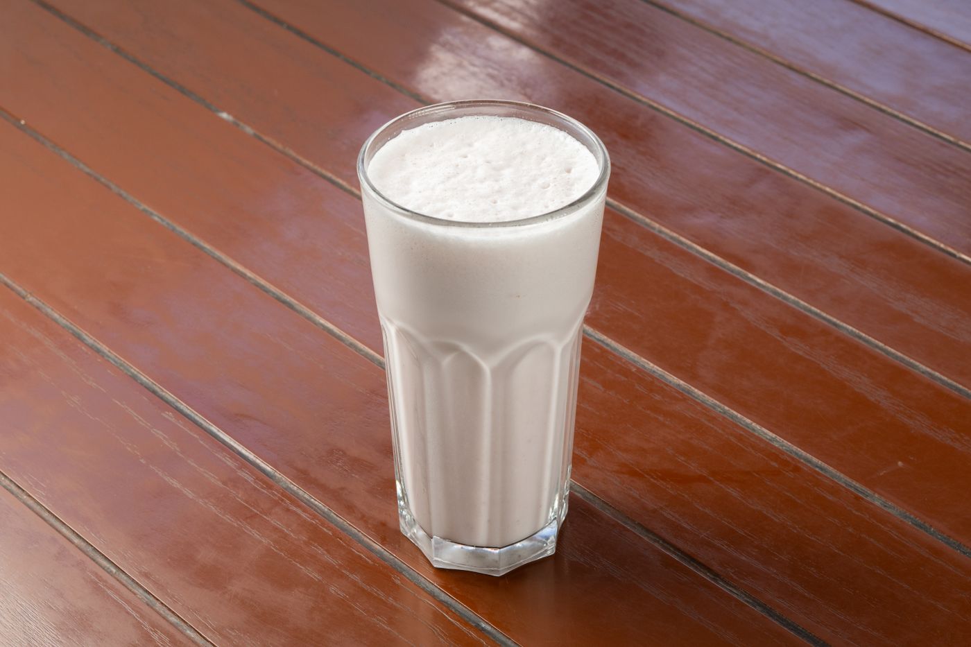 Milkshake vanille dans un verre posé sur une table en bois (photo d’illustration)